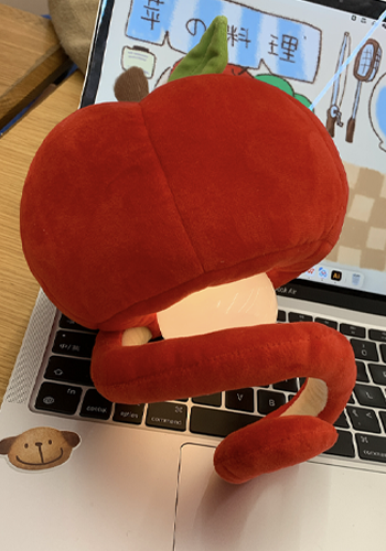 Red apple plush pendant lamp illuminated above a laptop