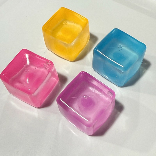 Four translucent TPR ice cube squishy toys photographed on a white surface